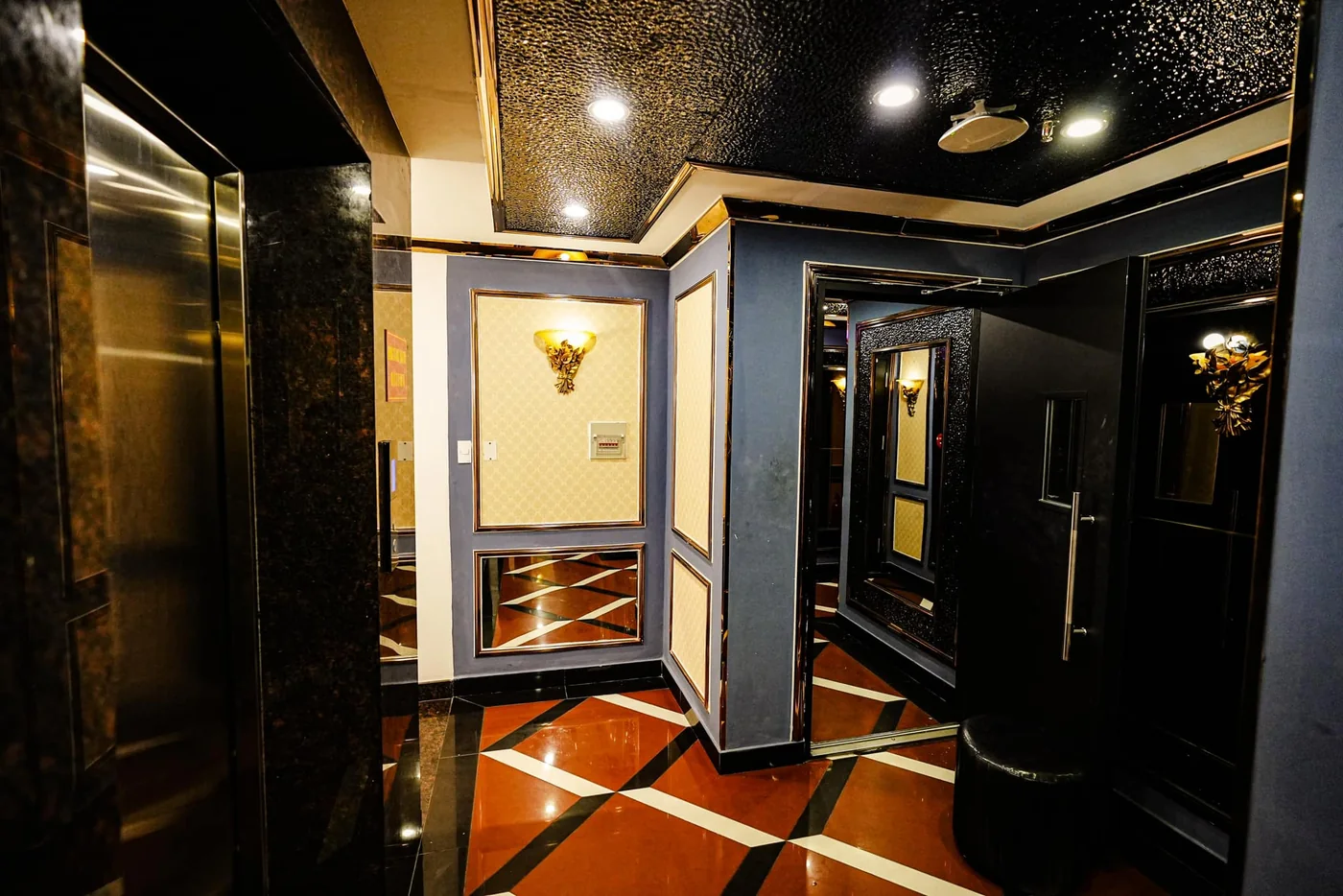 Lối vào phòng karaoke cạnh khu vực thang máy với nội thất đen vàng